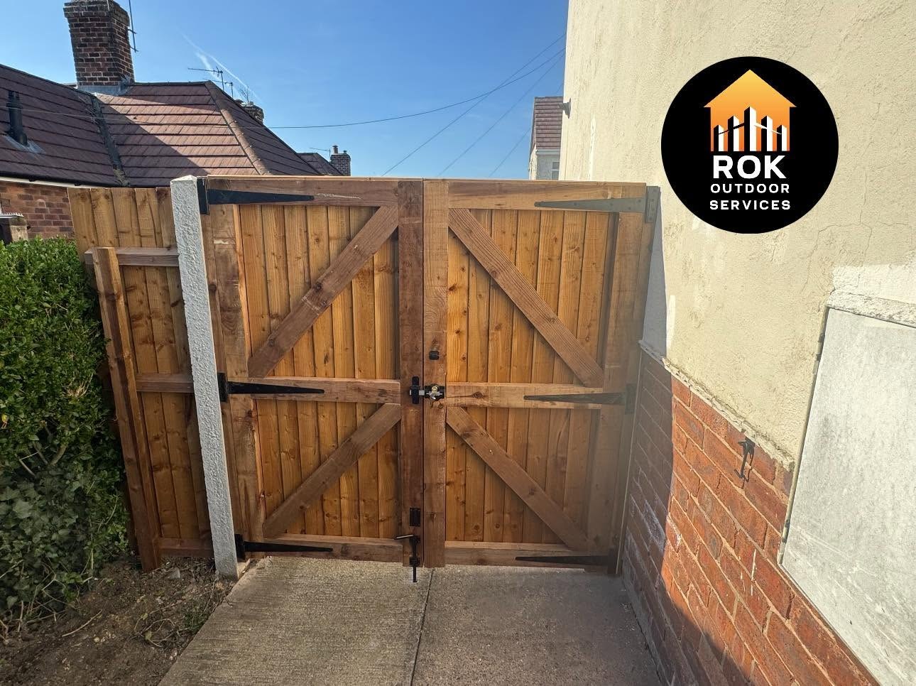 Double timber gates between a house and boundary fence